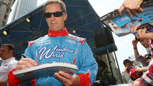 A man in blue and red racing suit holding a book.
