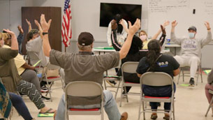A group of people sitting in chairs with their hands up.