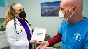 A doctor and a man wearing masks in an office.