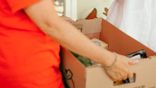 A person in an orange shirt is holding onto boxes